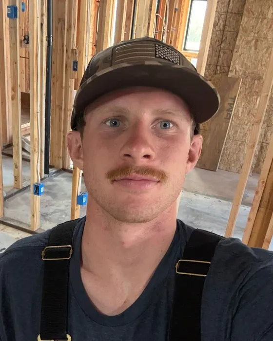 Jack, who runs Mapside Marketing, on a job site in a cap and work overalls